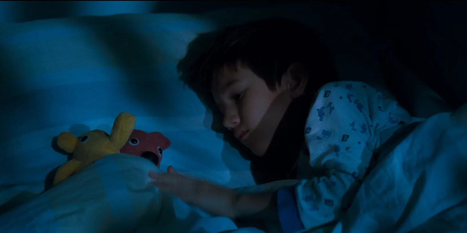 Kooky — a boy asleep in bed beside his toy