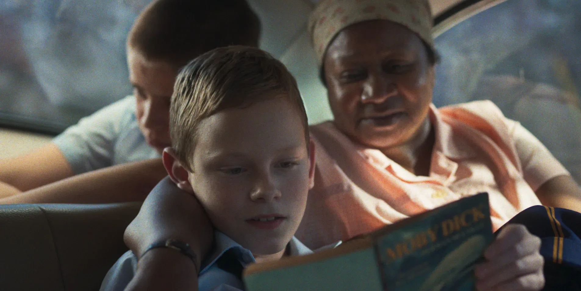 The Smell of Apples — a boy reading a book in a car beside a woman